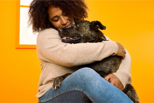 A woman cuddles a spotted dog
