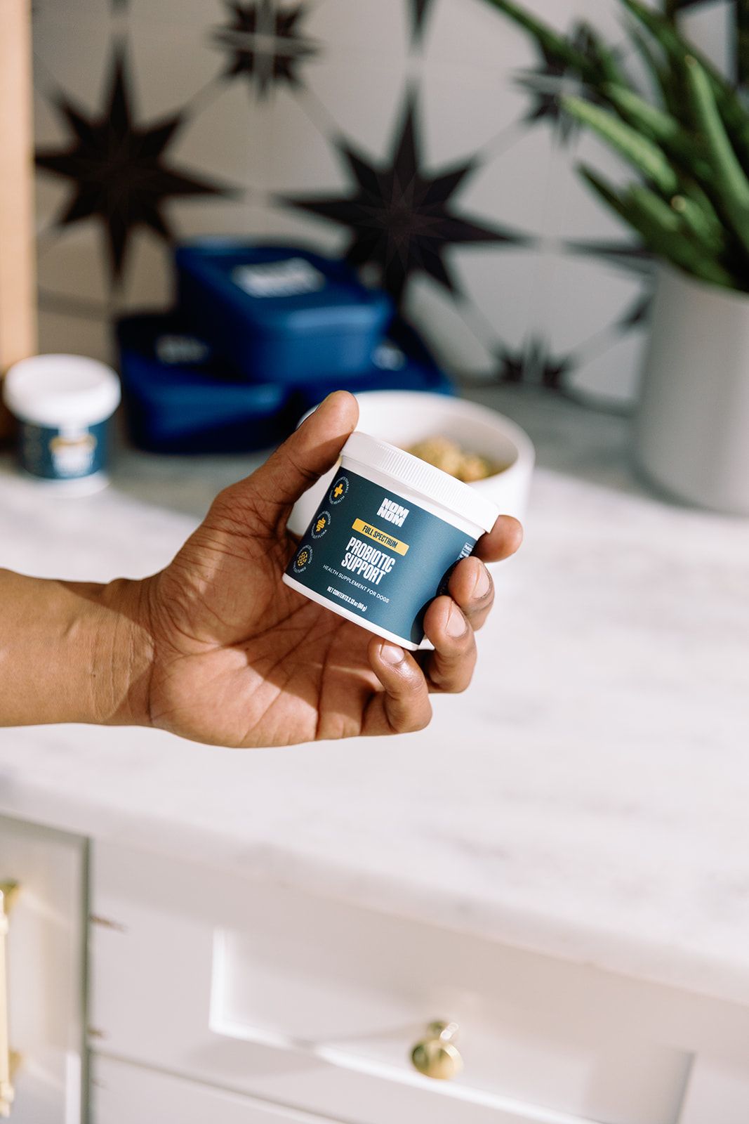 A hand holding a Full Spectrum Probiotic container
