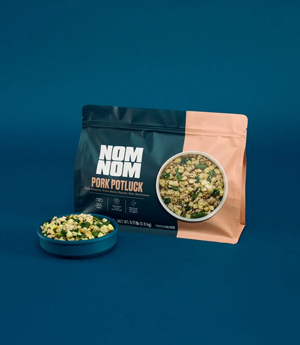 A dog eats a Pork Potluck meal from a bowl